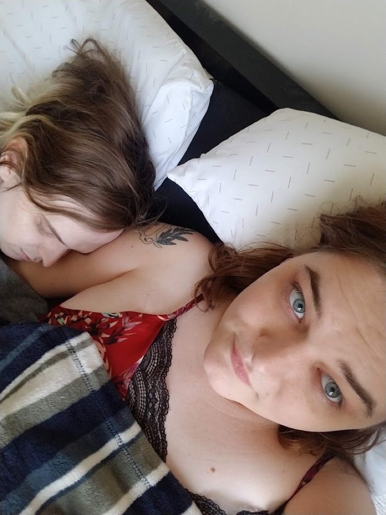 Kat takes a selfie lying in bed while Zoey sleeps nestled against her shoulder